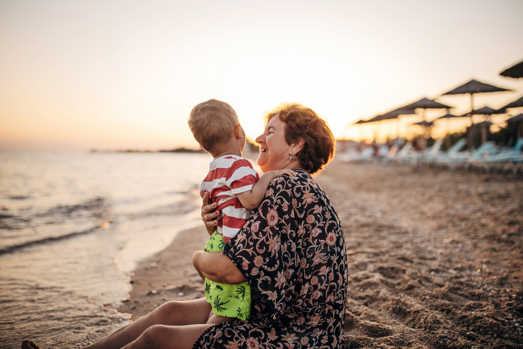 Grandmother and grandson on the sandy beach, summer vacation